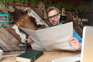 casual man holding the newspaper while looking at camera happy