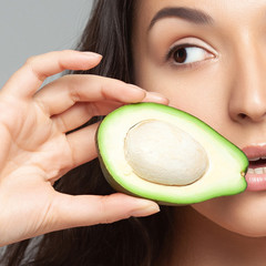 Young beautiful woman holding avocado