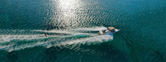 Obraz premium Aerial drone ultra wide photo of water skier cruising in high speed in tropical exotic bay