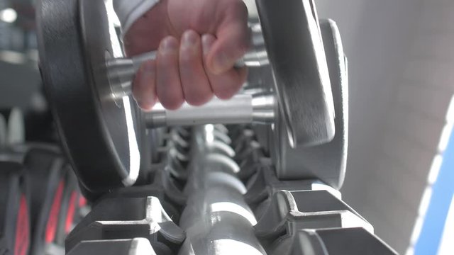 A man's hand takes a dumbbell in the gym. Close up. Muscular arm in the gym. Training, sports, hand, dumbbell. The concept of a healthy lifestyle.