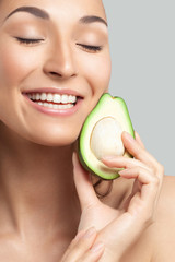 Young beautiful woman holding avocado