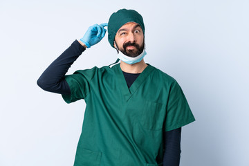 Fototapeta na wymiar Surgeon man in green uniform over isolated background having doubts