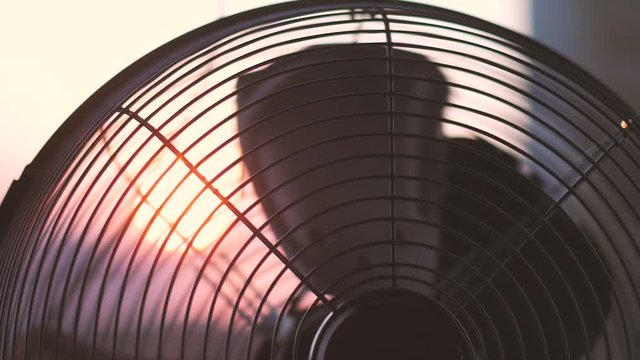 The electric fan is turned on in the evening in a stuffy room.