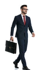 businessman walking with briefcase on hand looking ahead serious