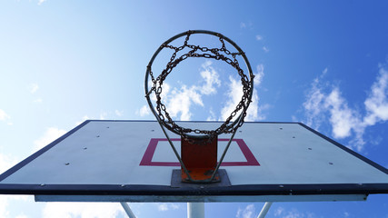 yard basketball hoop against the blue sky and white fluffy clouds. Basketball basket with chains in the open. street sport.