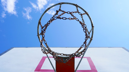 yard basketball hoop against the blue sky and white fluffy clouds. Basketball basket with chains in the open. street sport.