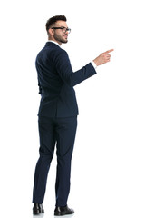 businessman standing with hand in pocket and pointing aside happy
