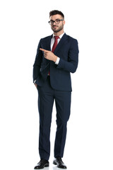 businessman standing with hand in pocket and pointing aside