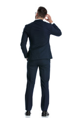 businessman standing and scratching head while pondering a decision