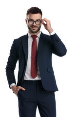 formal man standing with hand in pocket and fixing glasses