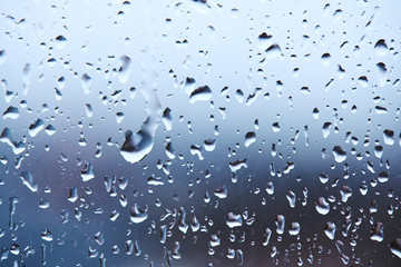 rain droplets on glass over calm colorful background. business backdrop