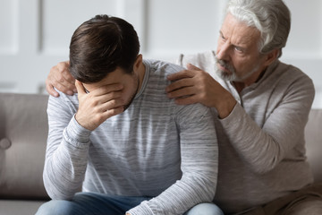 Caring elderly father hug comfort upset distressed grown-up son suffering from life relationship...