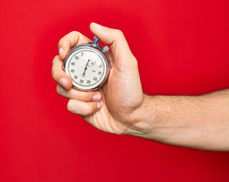Beautiful hand of man holding stopwatch doing countdown over isolated red background