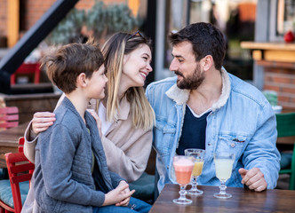 Father, mother and son sitting in a cafe having fun.