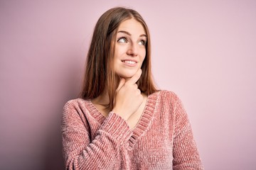 Fototapeta premium Young beautiful redhead woman wearing casual sweater over isolated pink background with hand on chin thinking about question, pensive expression. Smiling with thoughtful face. Doubt concept.