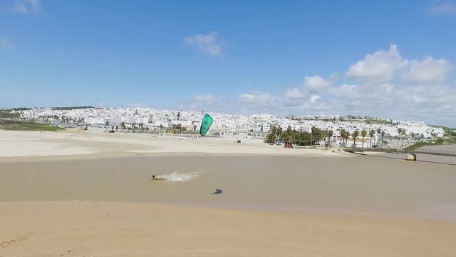 Aerial shot of a kitesurfer kiting in a lagoon in front of a white city and beach near Tarifa