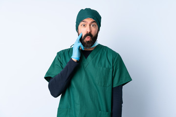 Surgeon man in green uniform over isolated background with surprise and shocked facial expression