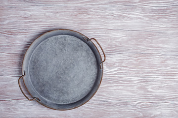 Vintage metal platter on gray wooden background top view with copy space