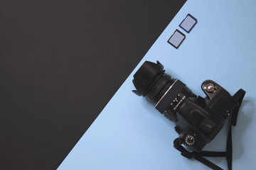 Modern photographer camera and memory on black and light blue background. 