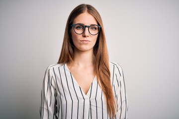 Young beautiful redhead woman wearing casual striped t-shirt and glasses with serious expression on face. Simple and natural looking at the camera.