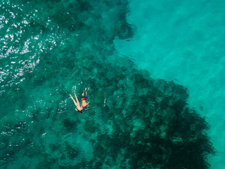 Fototapeta na wymiar Snorkeling couple in the middle of the Indian Ocean, coral reefs, green water, from high above. Birds eye view. 