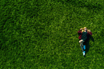 Fototapeta na wymiar Happy woman relaxing on the grass. Aerial top view of vacation during sunny summer day