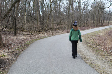 Woman walking with winter clothes on the North Branch Trail at Linne Woods in Morton Grove, Illinois
