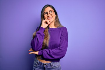 Young beautiful smart woman wearing glasses over purple isolated background with hand on chin thinking about question, pensive expression. Smiling and thoughtful face. Doubt concept.