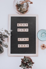 Words stay home, stay safe made of wooden blocks, concept of self quarantine at home as preventative measure against virus outbreak. Flat lay with inspiration quote, staying at home during pandemic