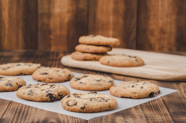 Cookies with chocolate filling on baking paper and wooden table/Cookies with chocolate filling on baking paper and wooden table. Fresh pastries. Copy space.