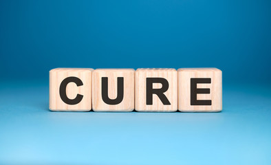 CURE - text on wooden blocks, medical concept, blue background