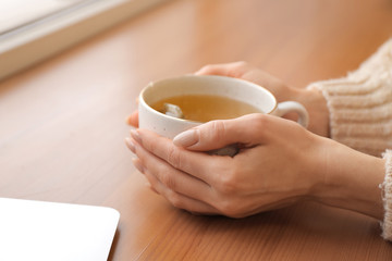 Beautiful young woman drinking tea at home, closeup