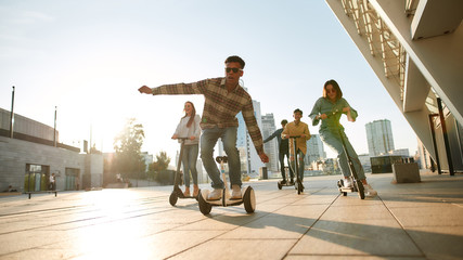 Let the life roll. A group of friends riding kick scooters and segways on a sunny day