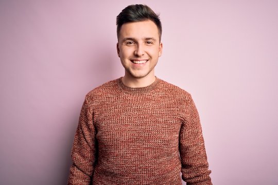 Young handsome caucasian man wearing casual winter sweater over pink isolated background with a happy and cool smile on face. Lucky person.