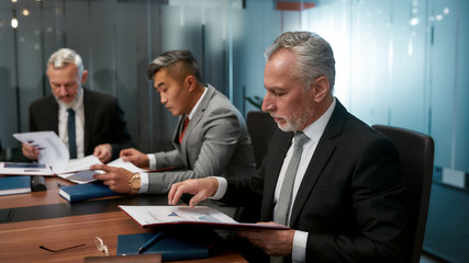 Paperwork. Group of multicultural business people reading documents while having a meeting in the office