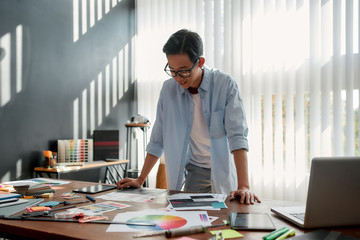 Satisfied with my work. Happy asian man in eyeglasses analyzing new design project and smiling...