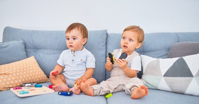 Beautiful toddlers sitting on the sofa playing with toys at home