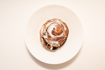 bun with raisins in white plate on white background