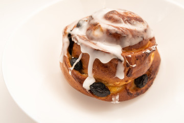 bun with raisins in white plate on white background