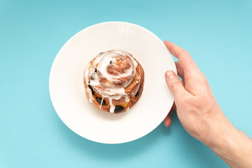 bun with raisins in white plate on blue background