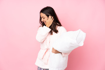 Young woman in pajamas isolated on pink background laughing