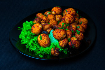 baked champignons in a dark plate on a dark background