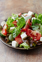  Healthy salad with feta cheese, green olives and tomatoes. Rustic stone background. Close up. 