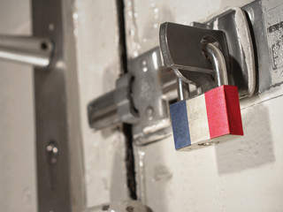 A bolted door secured by a padlock with the national flag of French Guiana on it.(series)