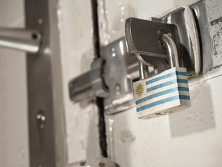 A bolted door secured by a padlock with the national flag of Uruguay on it.(series)