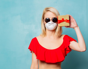 Blonde woman in bikini and face mask with gift box