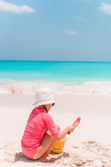 Adorable little girl playing with beach toys on white tropial beach