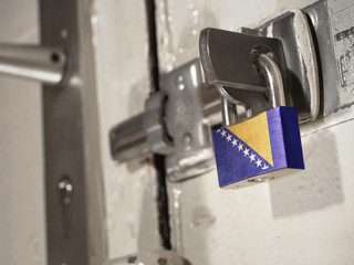 A bolted door secured by a padlock with the national flag of Bosnia and Herzegovina on it.(series)