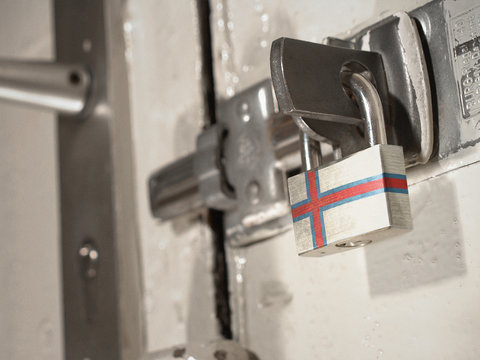A bolted door secured by a padlock with the national flag of Faroe Islands on it.(series)