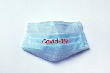 blue medical protective mask on a gray background with inscription Covid-19, concept accessory for coronavirus protection